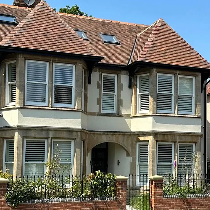 A large house with many windows and a fence in front of it.