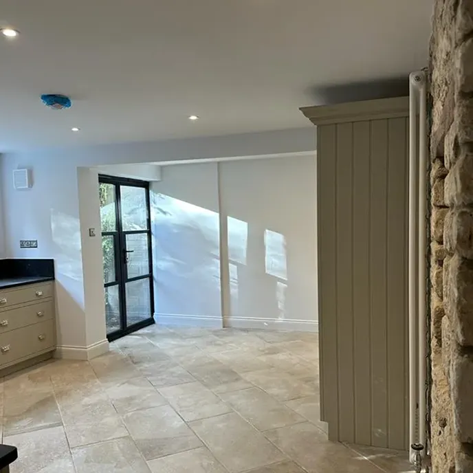 A kitchen with a stone wall and a large window.